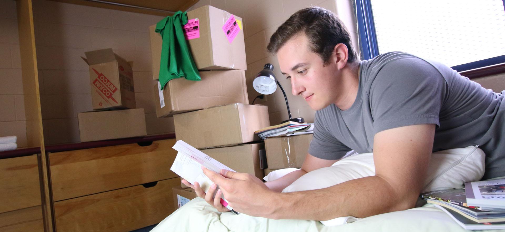 Boy looking at book laying on bed