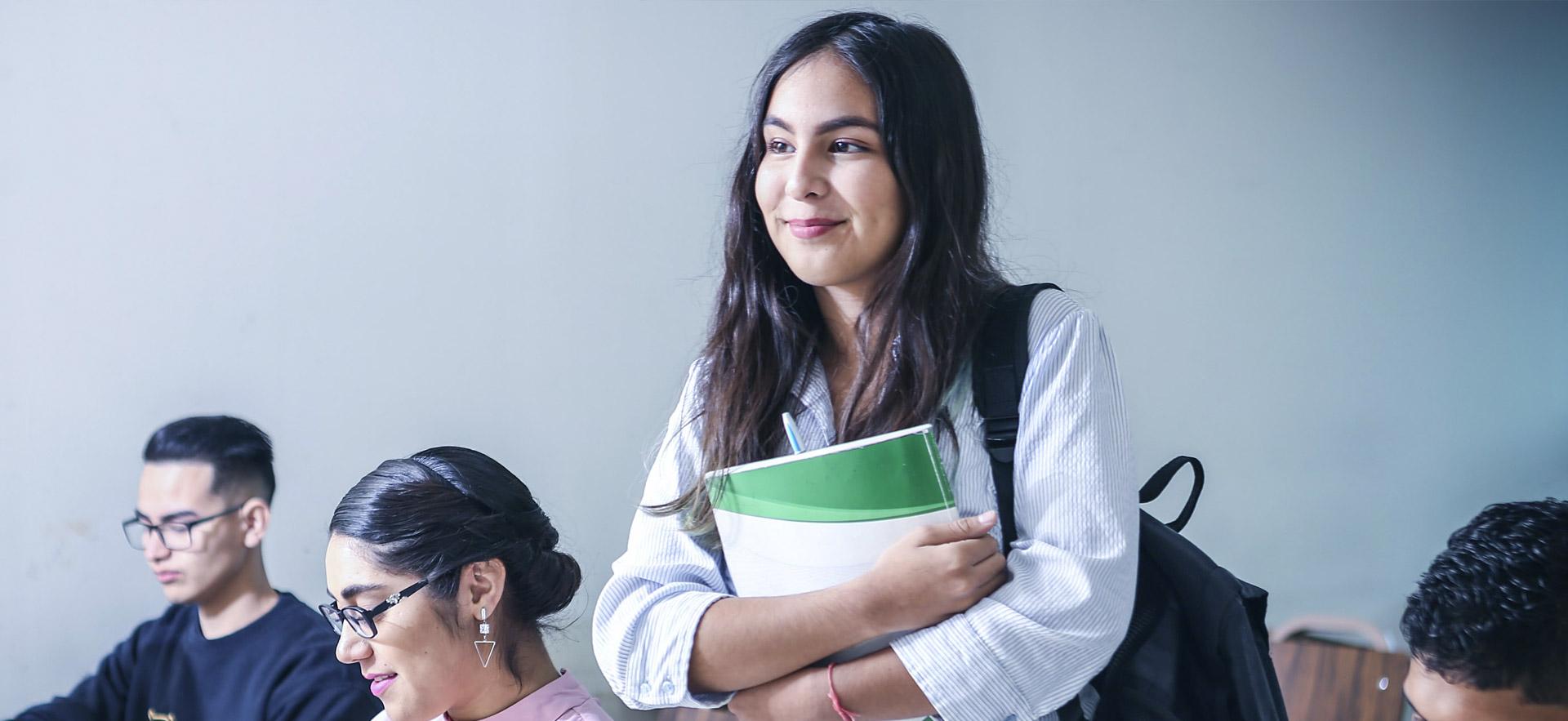 Female high school student smiling and standing in class.