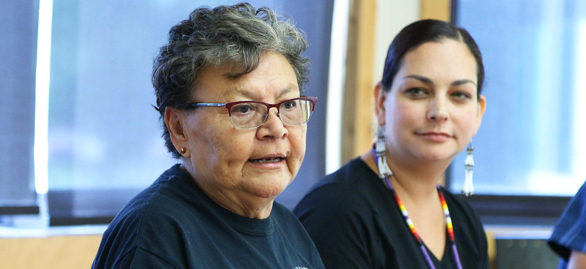 indigenous elder speaking beside younger indigenous person