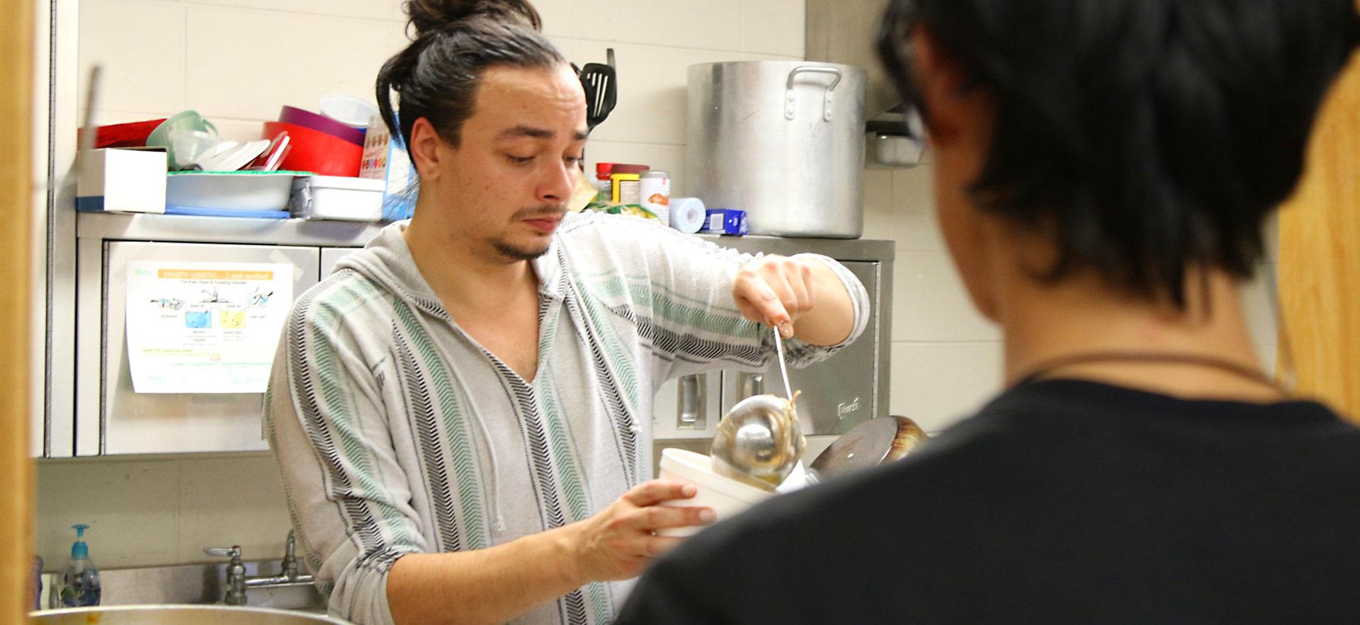 indigenous student in kitchen pouring soup into a cup
