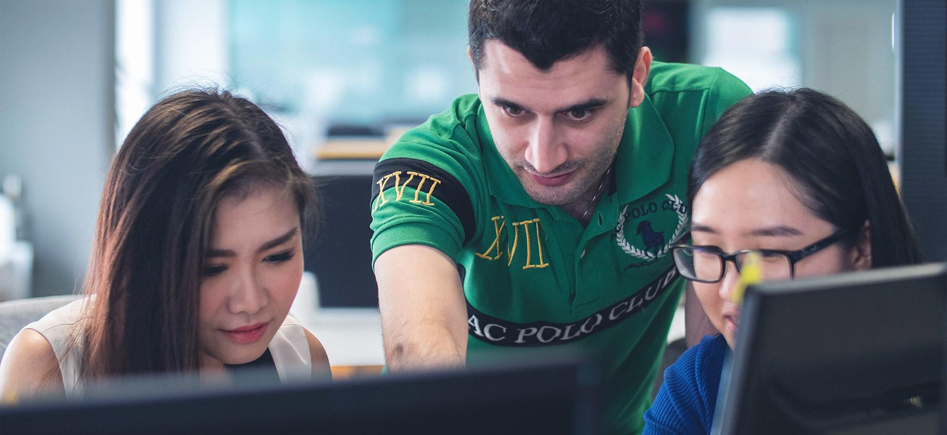 Three international students looking at a computer.