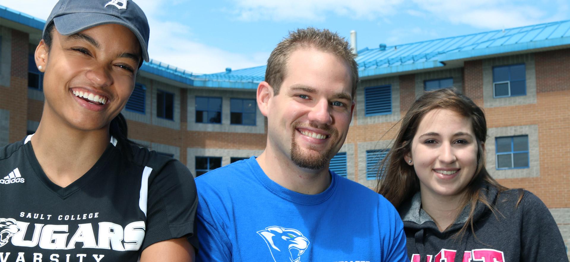 A group of students smiling in front of residence.