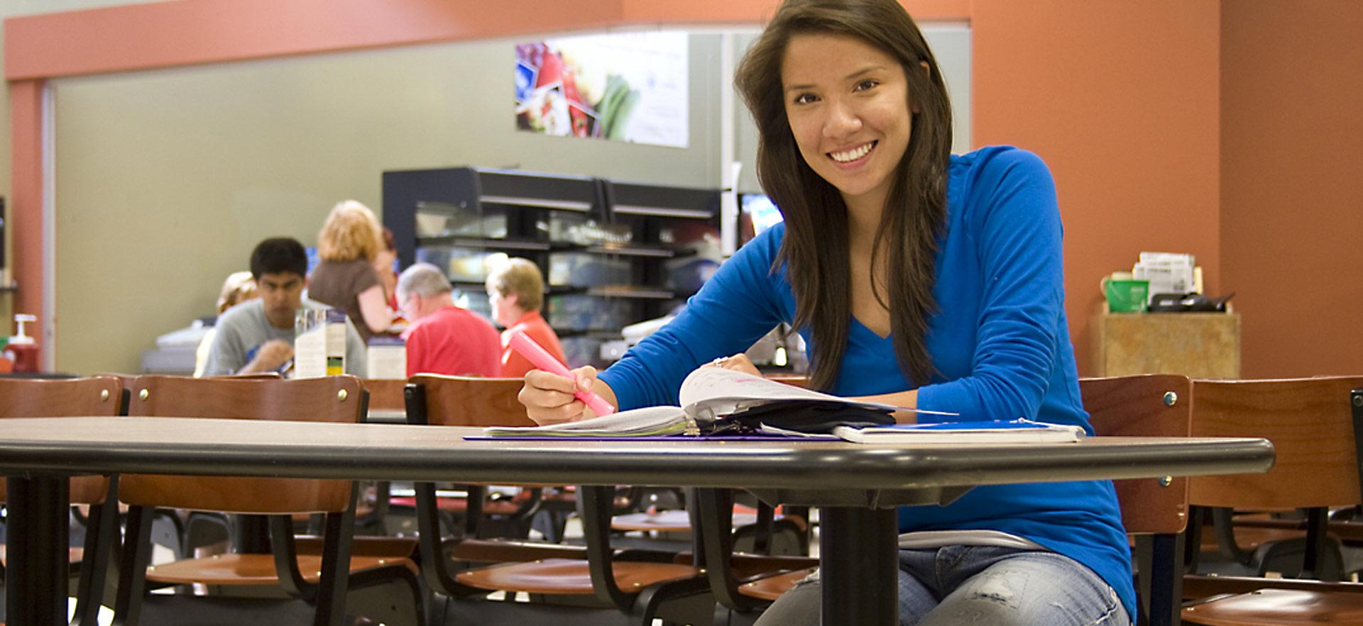 student smiling and sitting in cafeteria