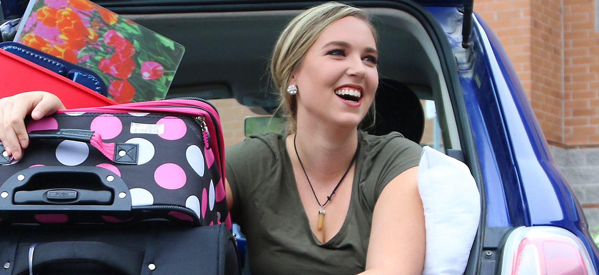 student smiling with suitcase