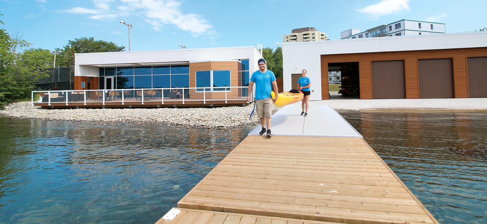 Students walking on a dock carrying a kayak