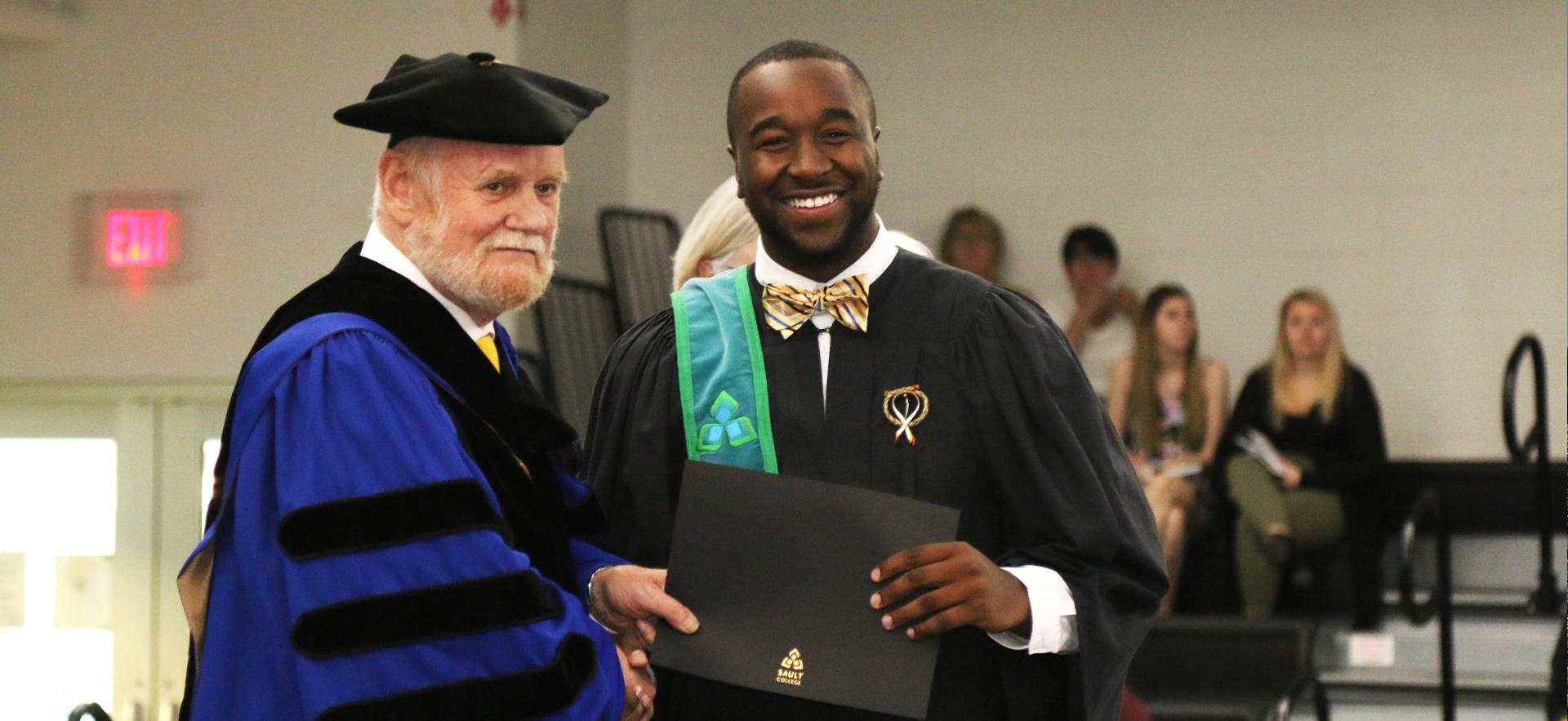 Male student receiving diploma at graduation.