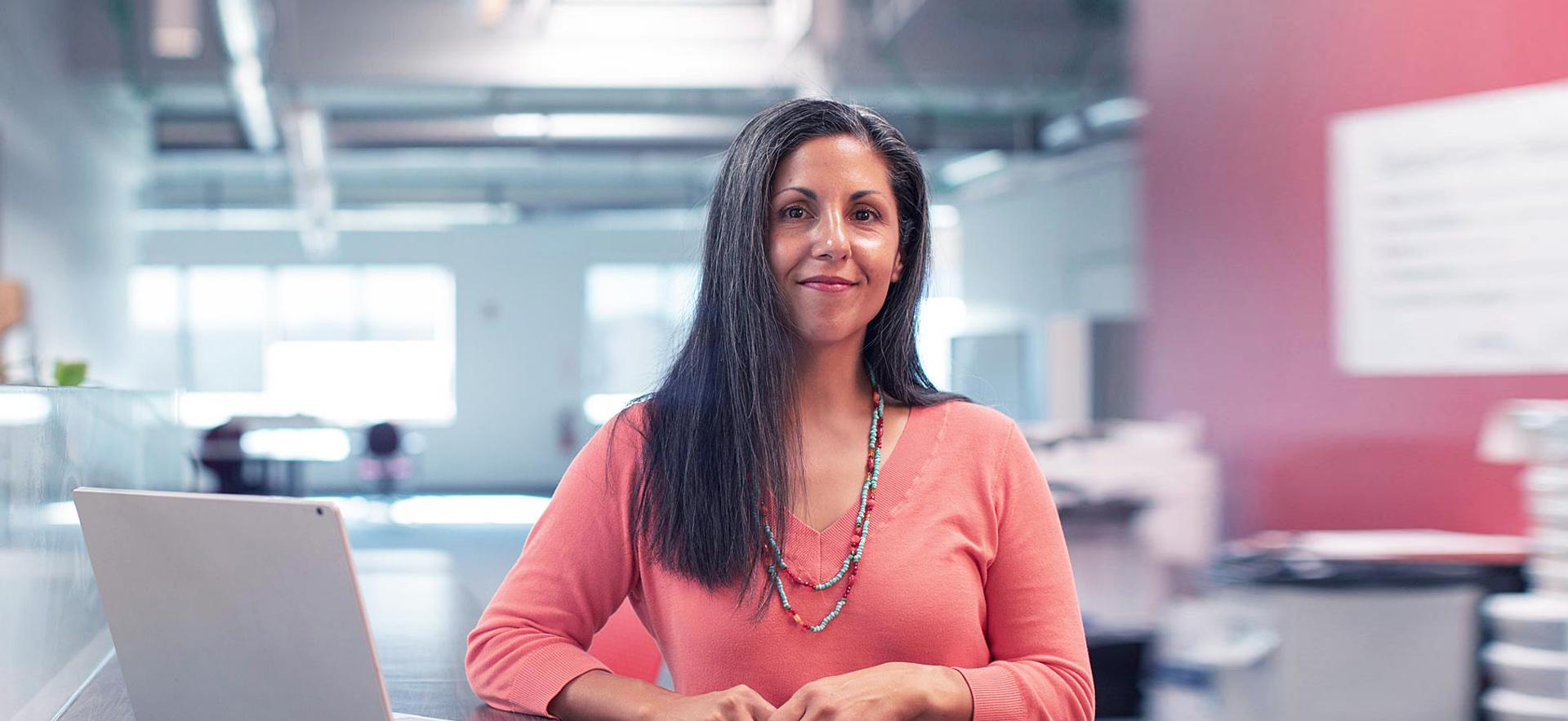 A female office worker poses for a smile in an office setting.