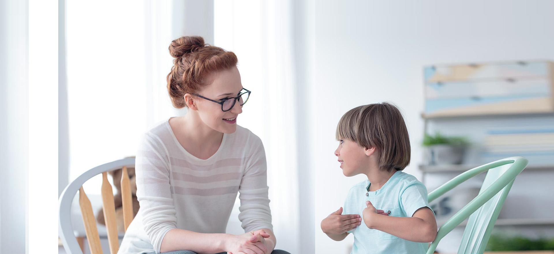 Female adult counselling a young boy.