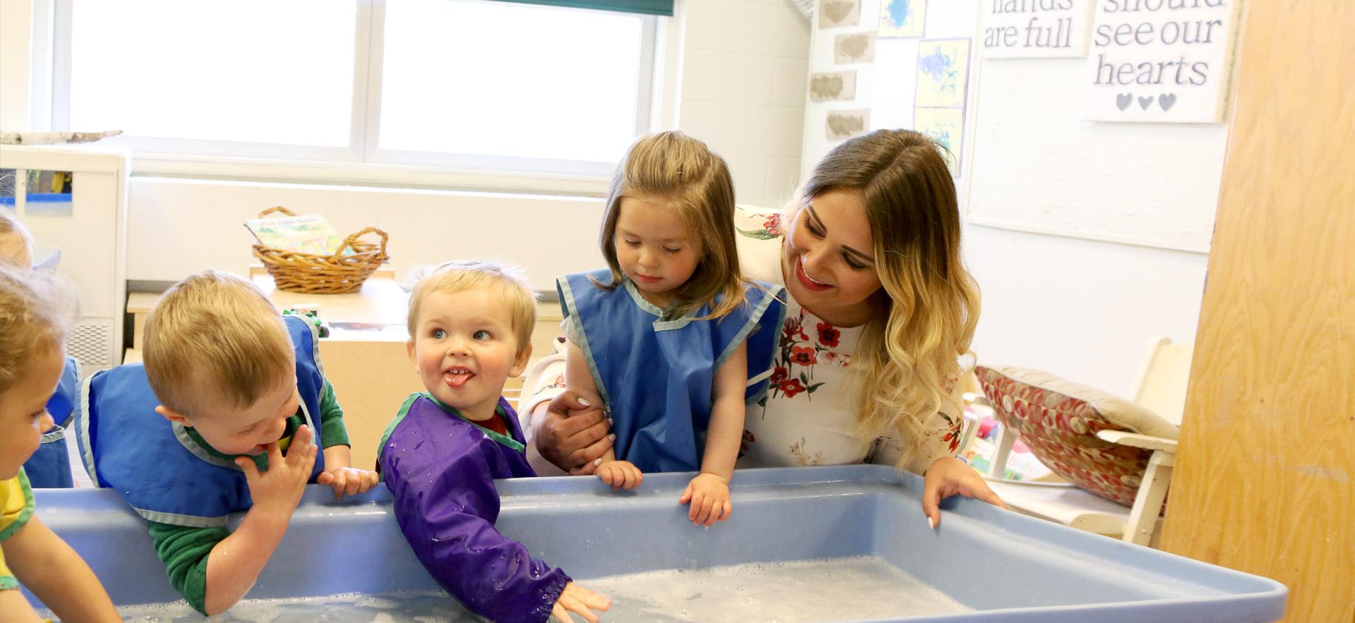 Female childcare worker playing with young children.