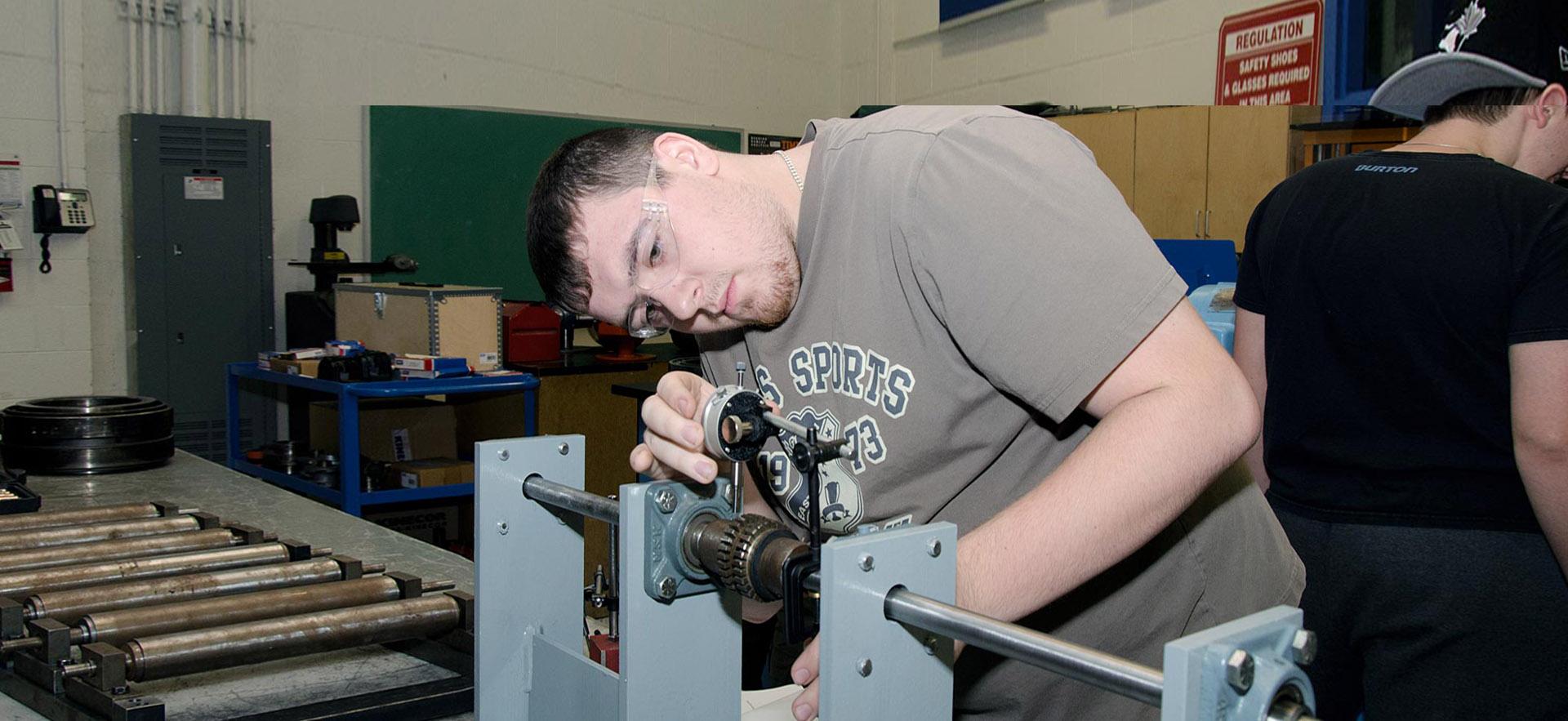 A male Instrumentation and Control Engineering Technician takes a careful measurement. 