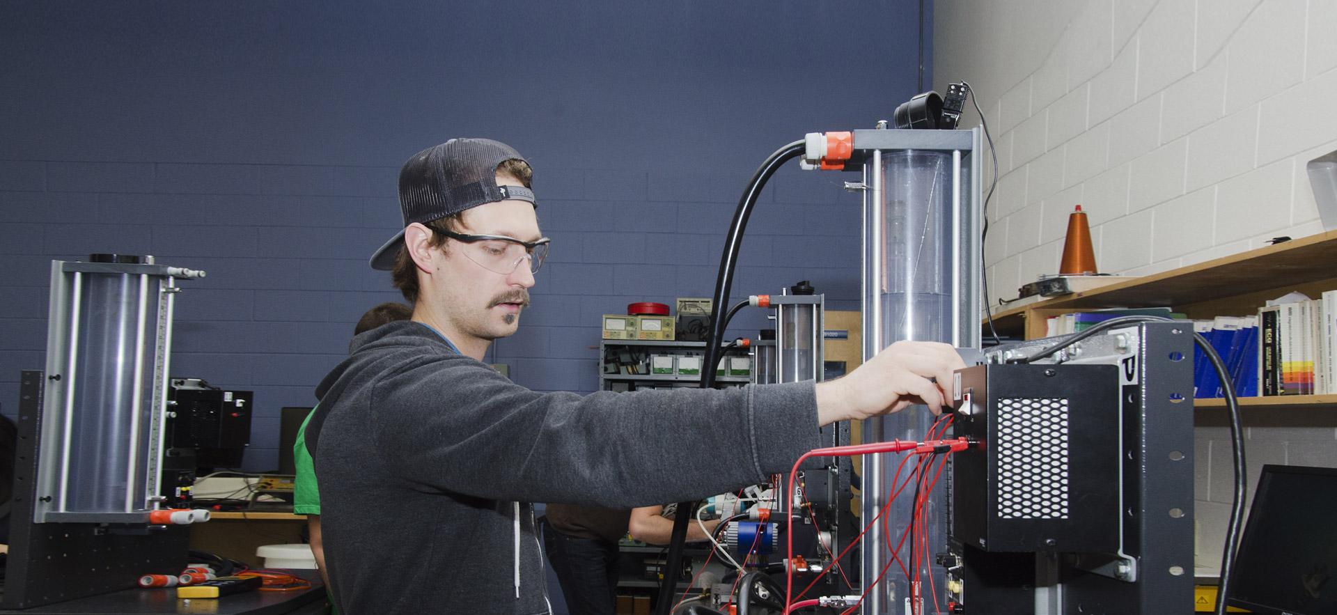 A male Electrical Engineering Technician - Process Automation and Trades checks his instruments. 