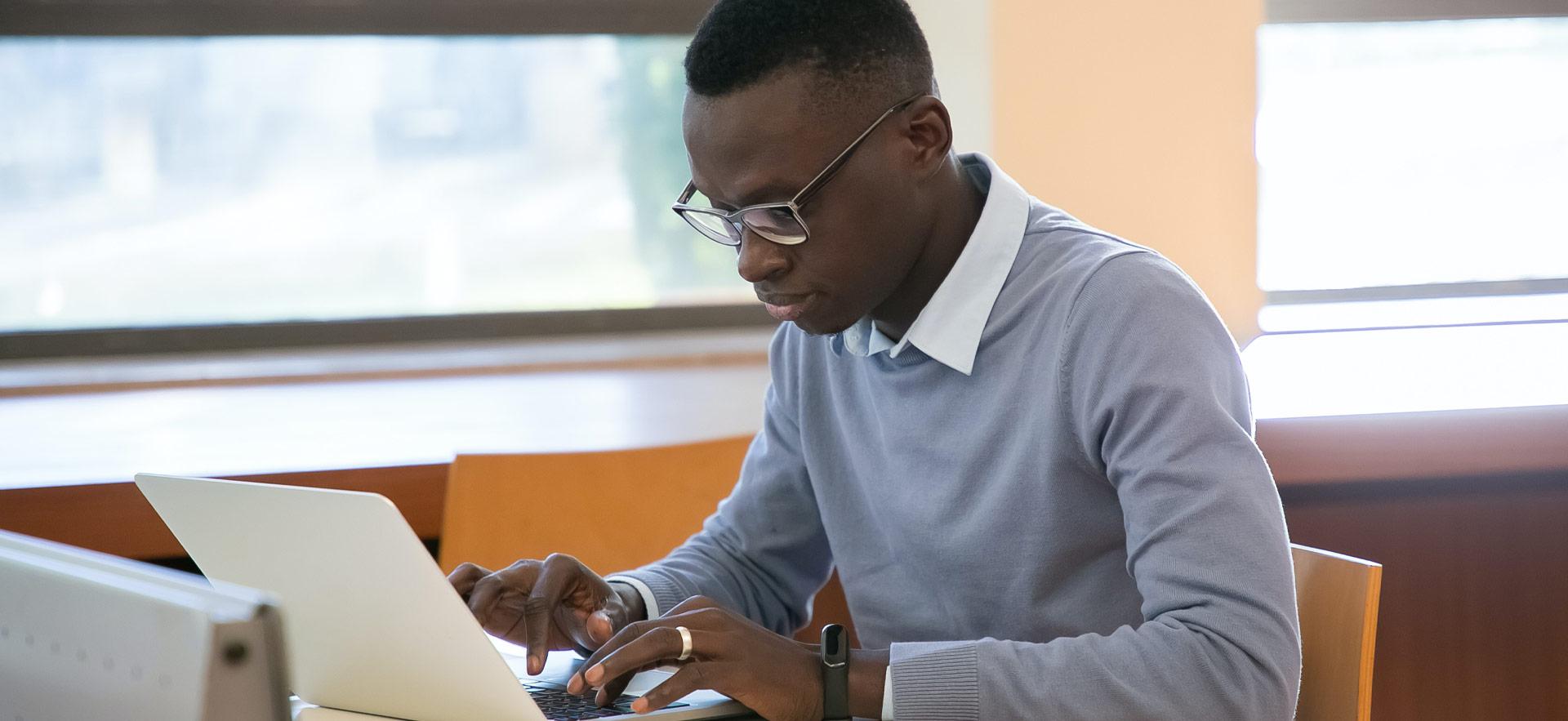 male students at work station typing on laptop