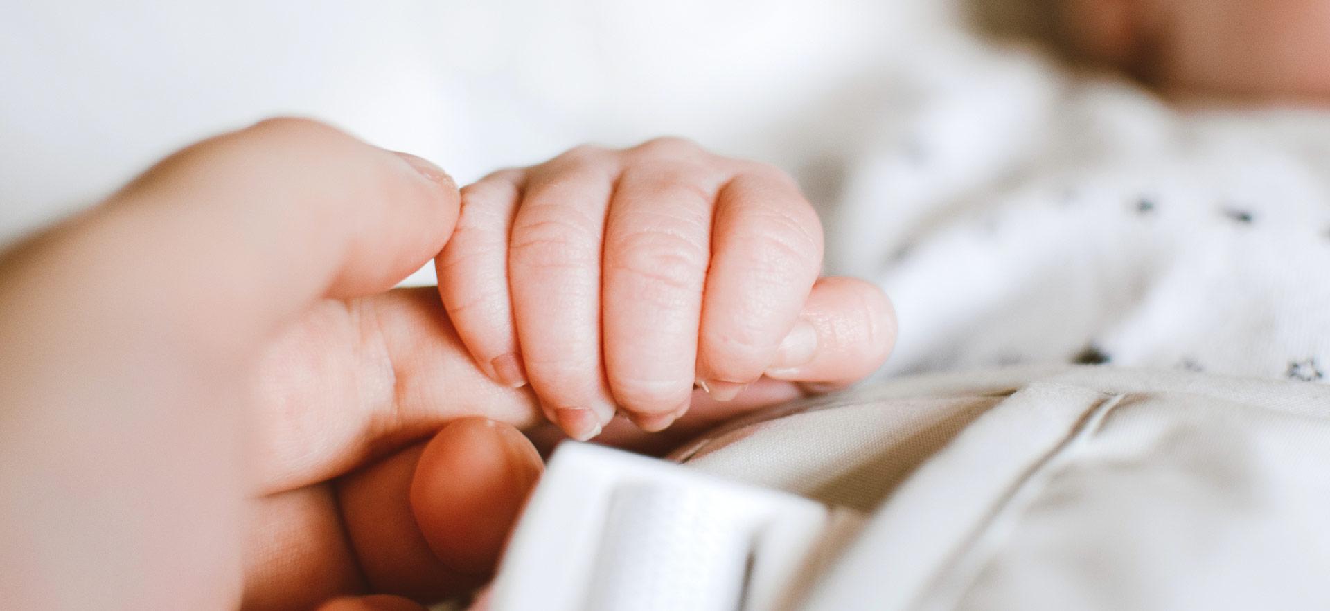 mother's hand holding baby's hand