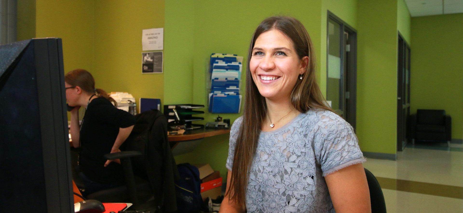 female staff smiling at computer terminal in office