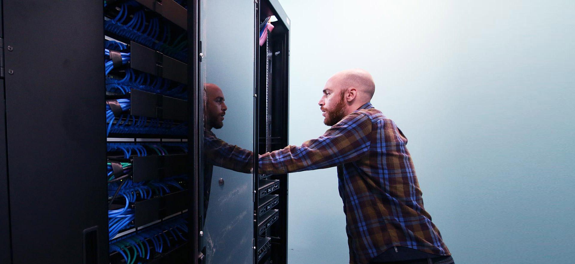 Male computer technician reviews a Sault College computer server.