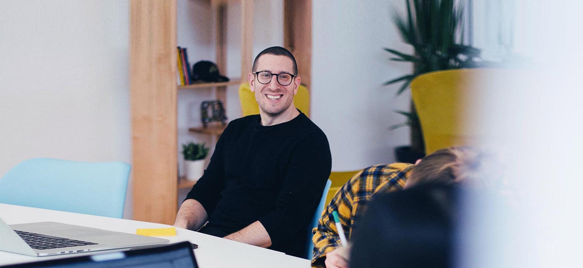 Male marketing specialist smiling during a meeting.