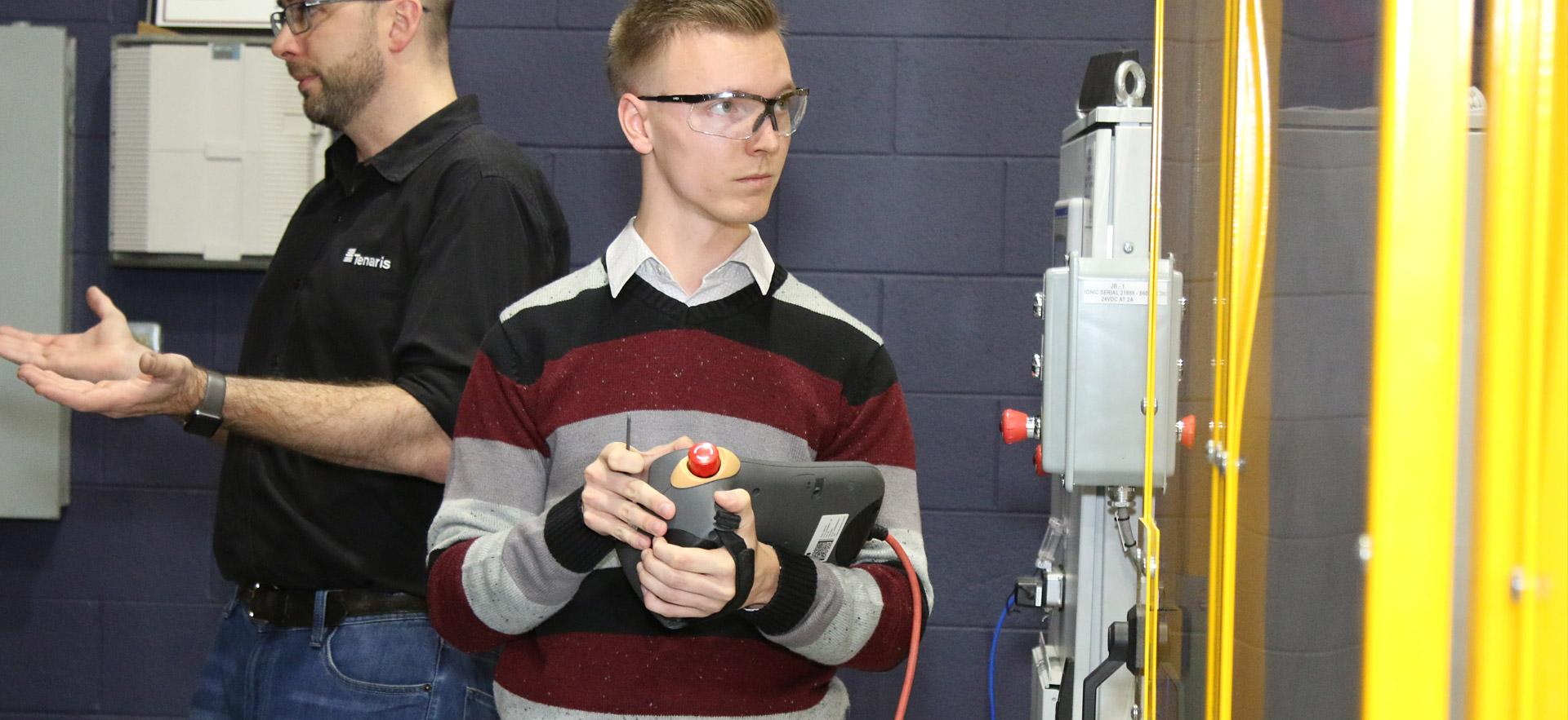 A male student demonstrating a year-end assignment in robotics.