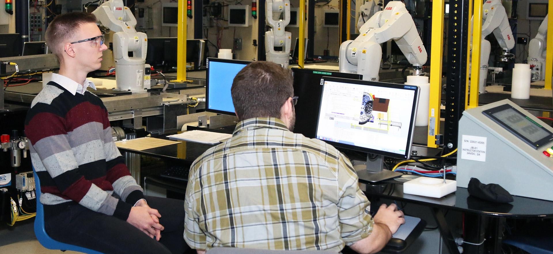 Two male students demonstrating a year-end assignment in robotics.