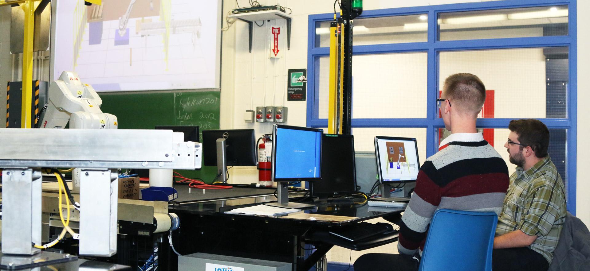 Two male students demonstrating a year-end assignment in robotics.