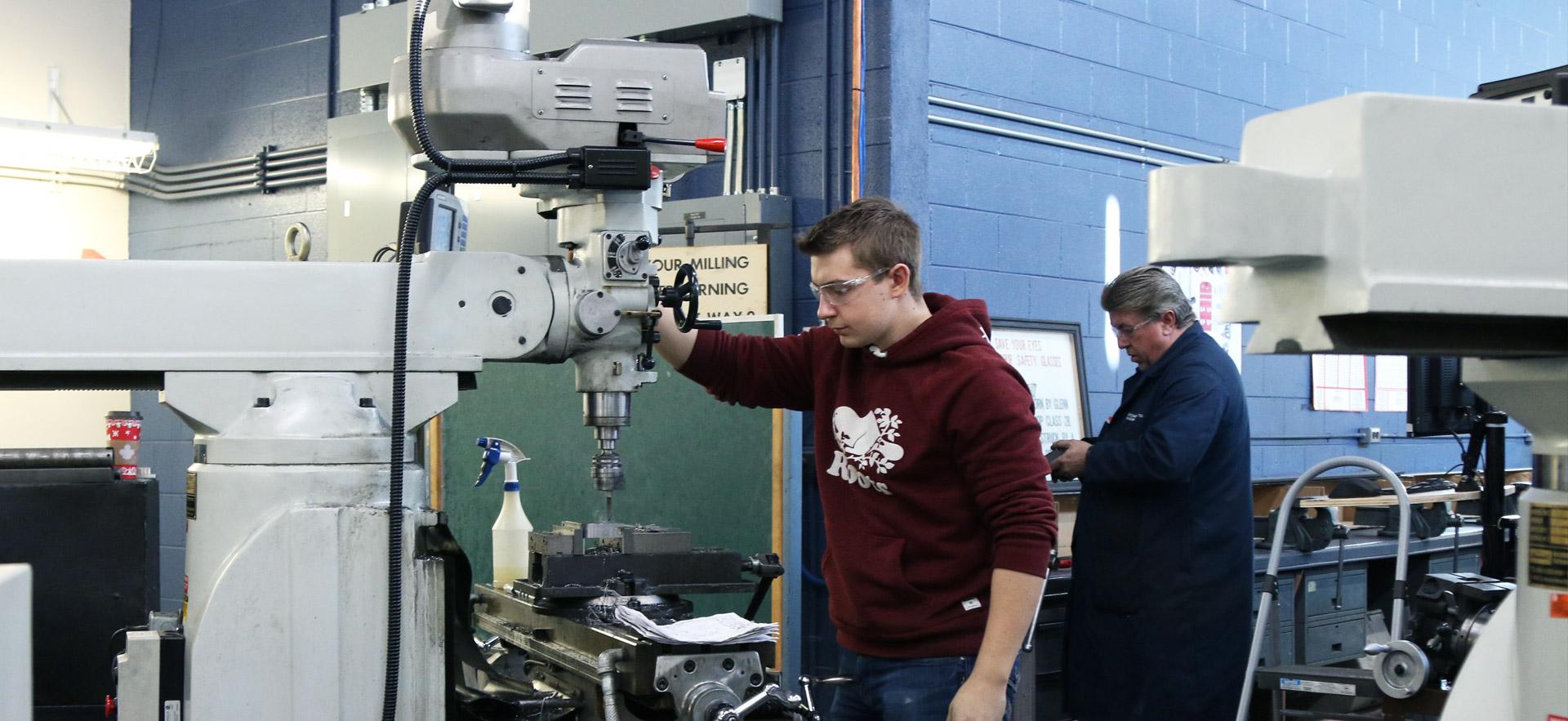 Male student working on a drill press.