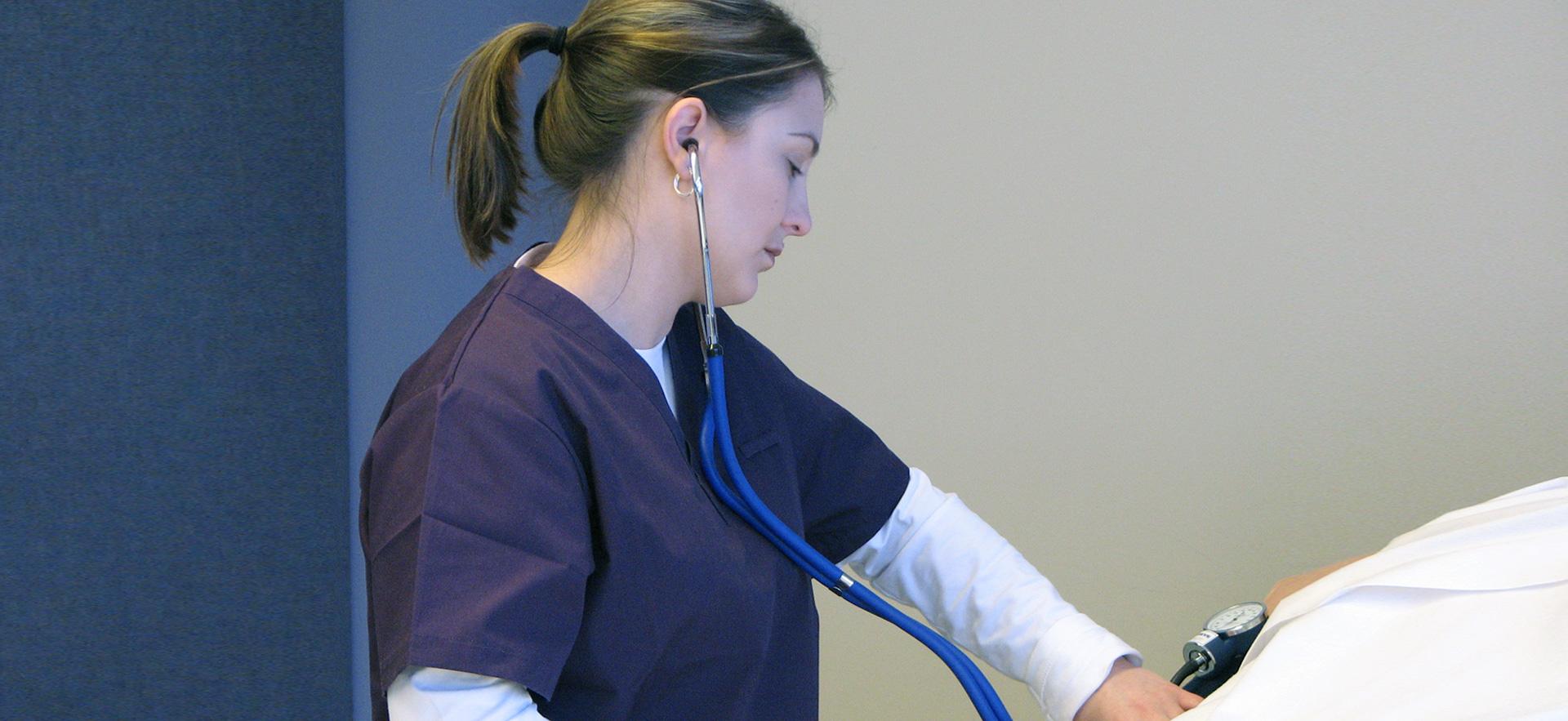 Female Practical Nursing student checking blood pressure.