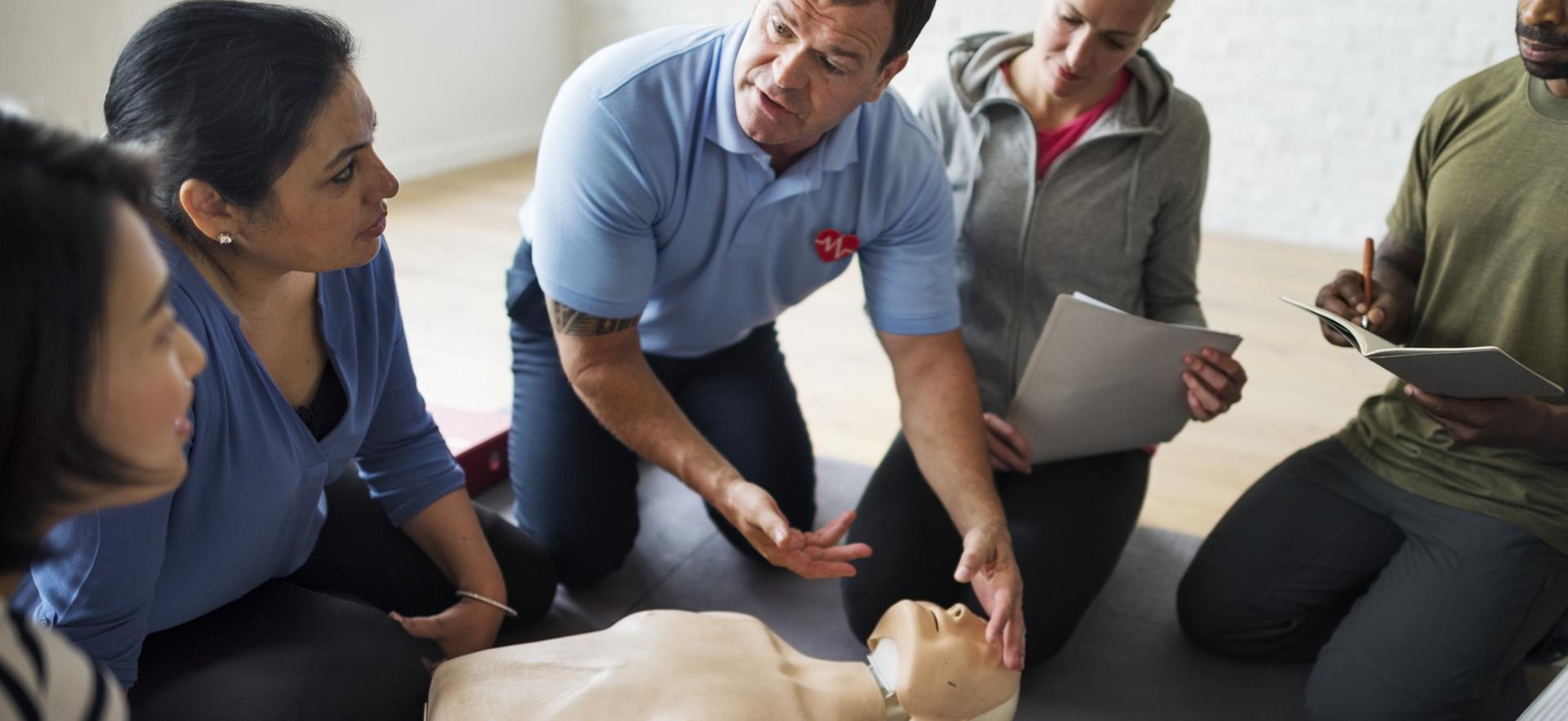 Instructor showing students CPR techniques on mannequin 
