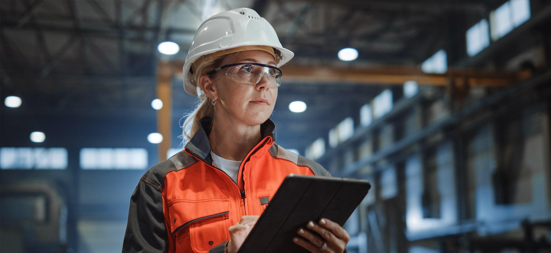 Woman with hard hat and clipboard in manufacturing plant