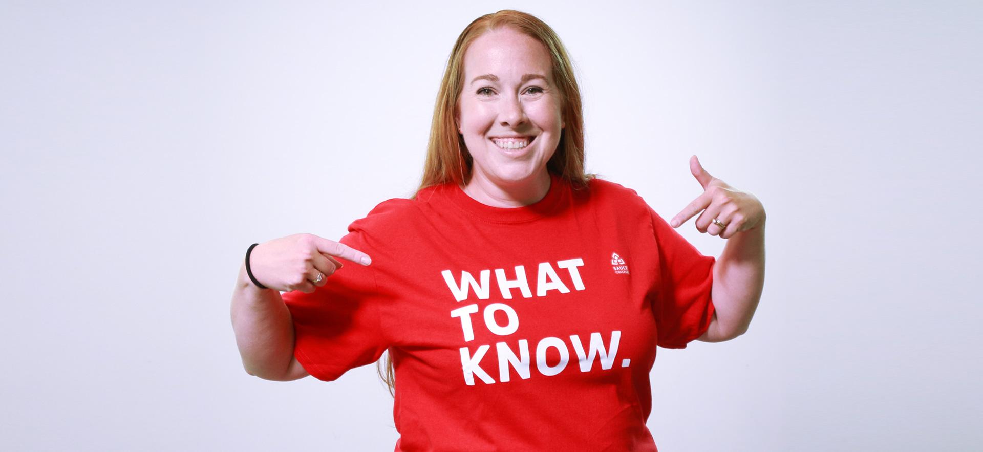 Image of student recruiter poitning to what to know shirt