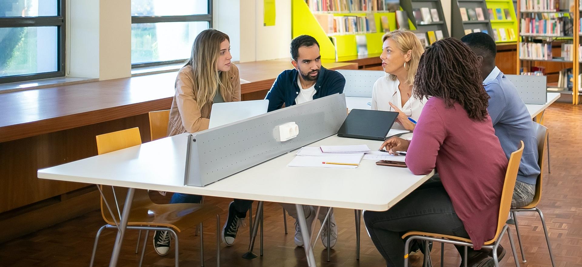 Teacher at a desk with four students in discussion