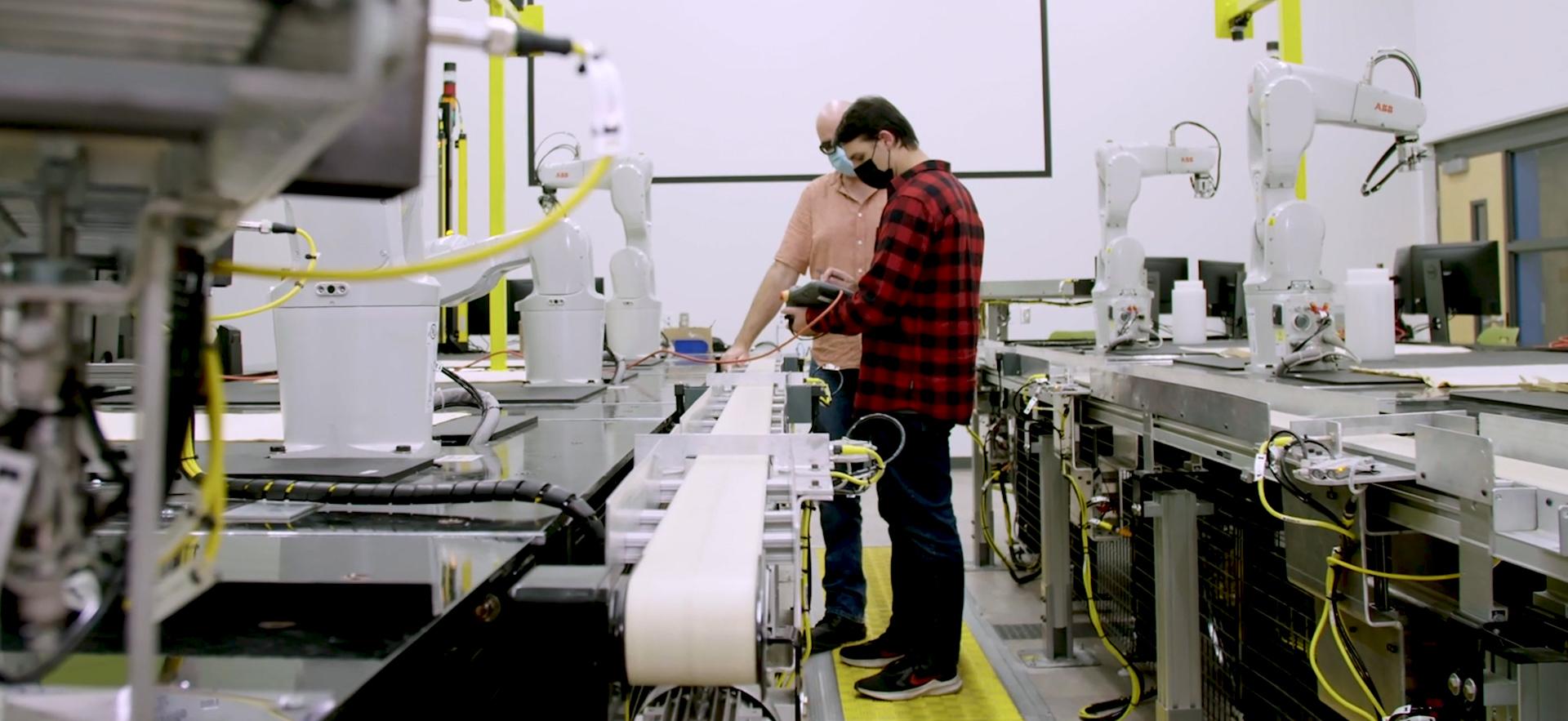 Student and instructor in mechatronics lab with multiple robot arms