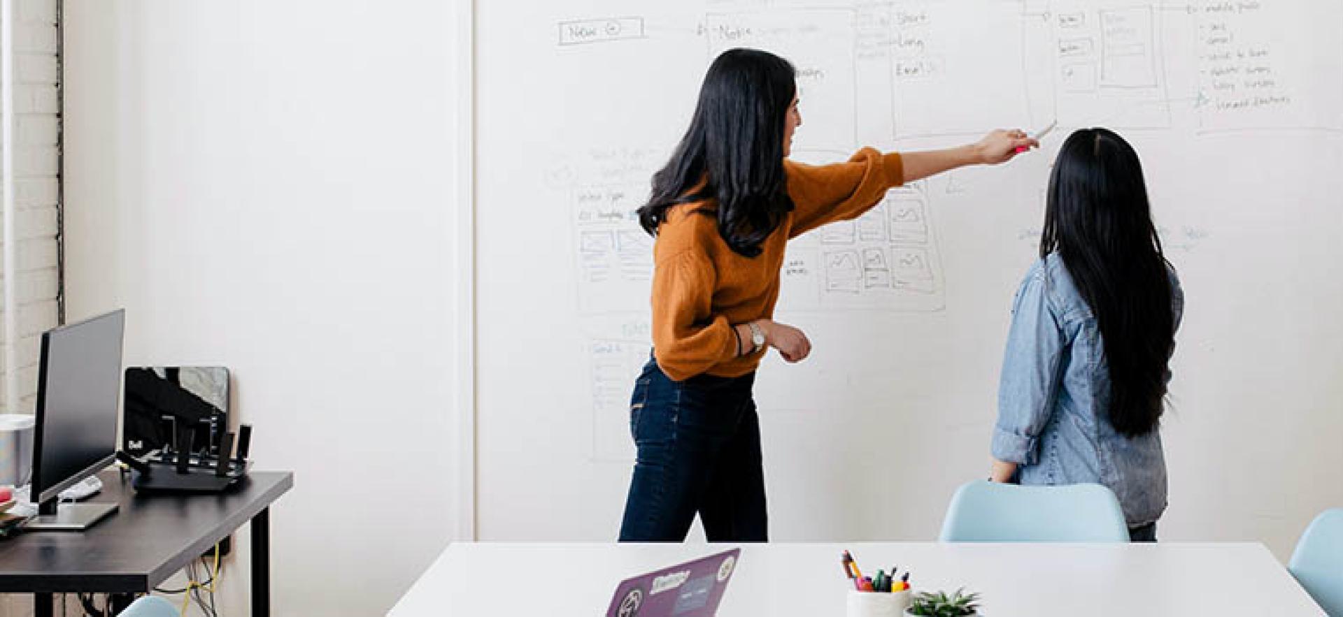 Person pointing on a whiteboard with a peer