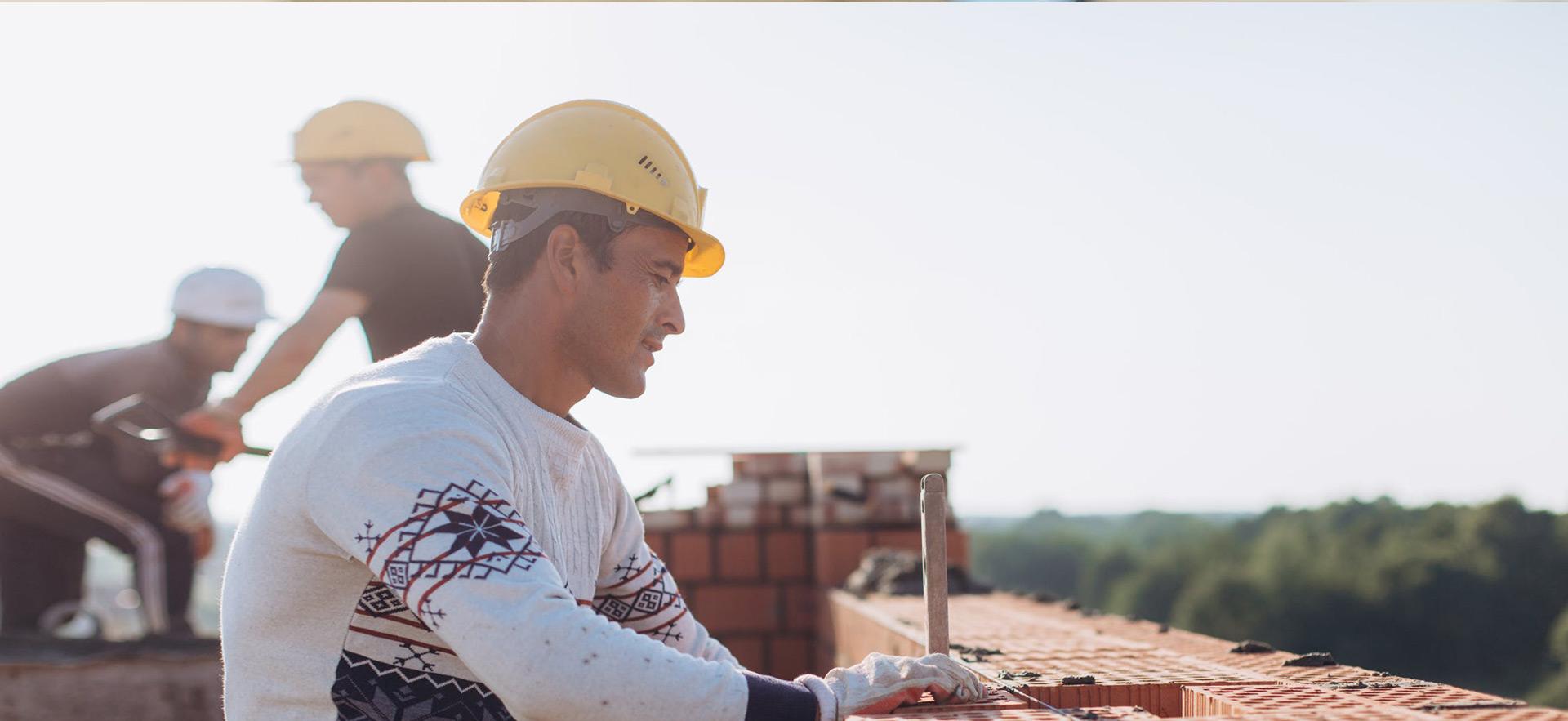Male working on a roof laying bricks.