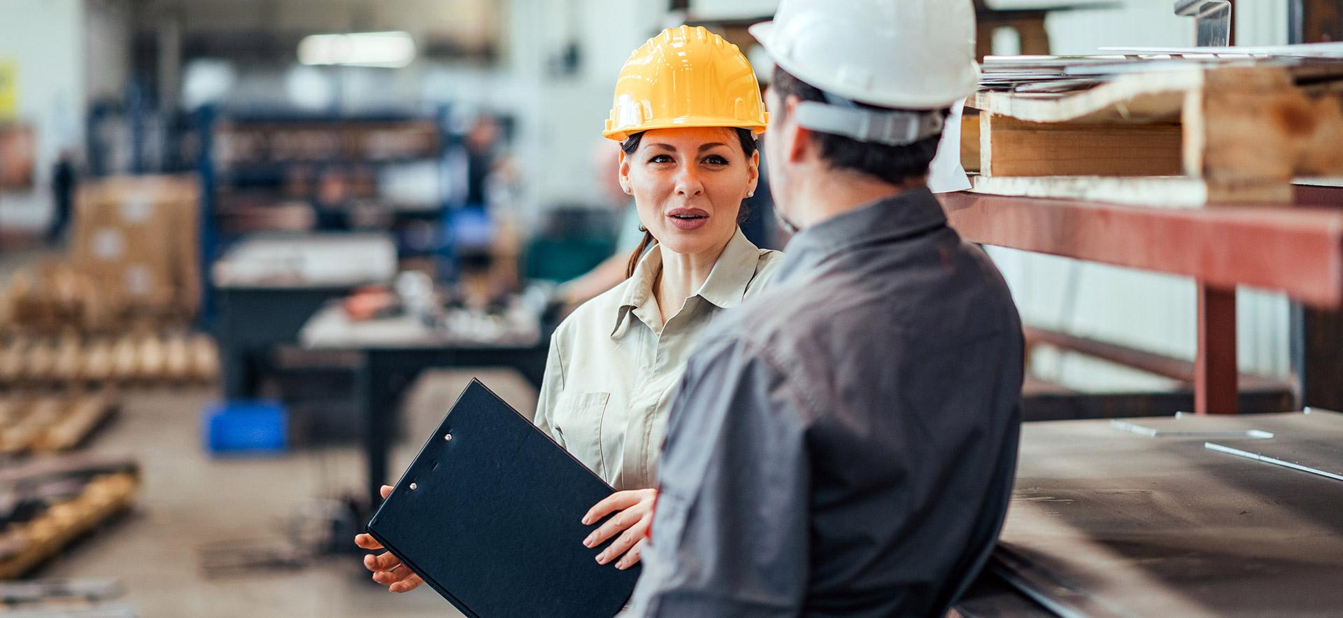 woman and man speaking in a manufacturing warehouse setting