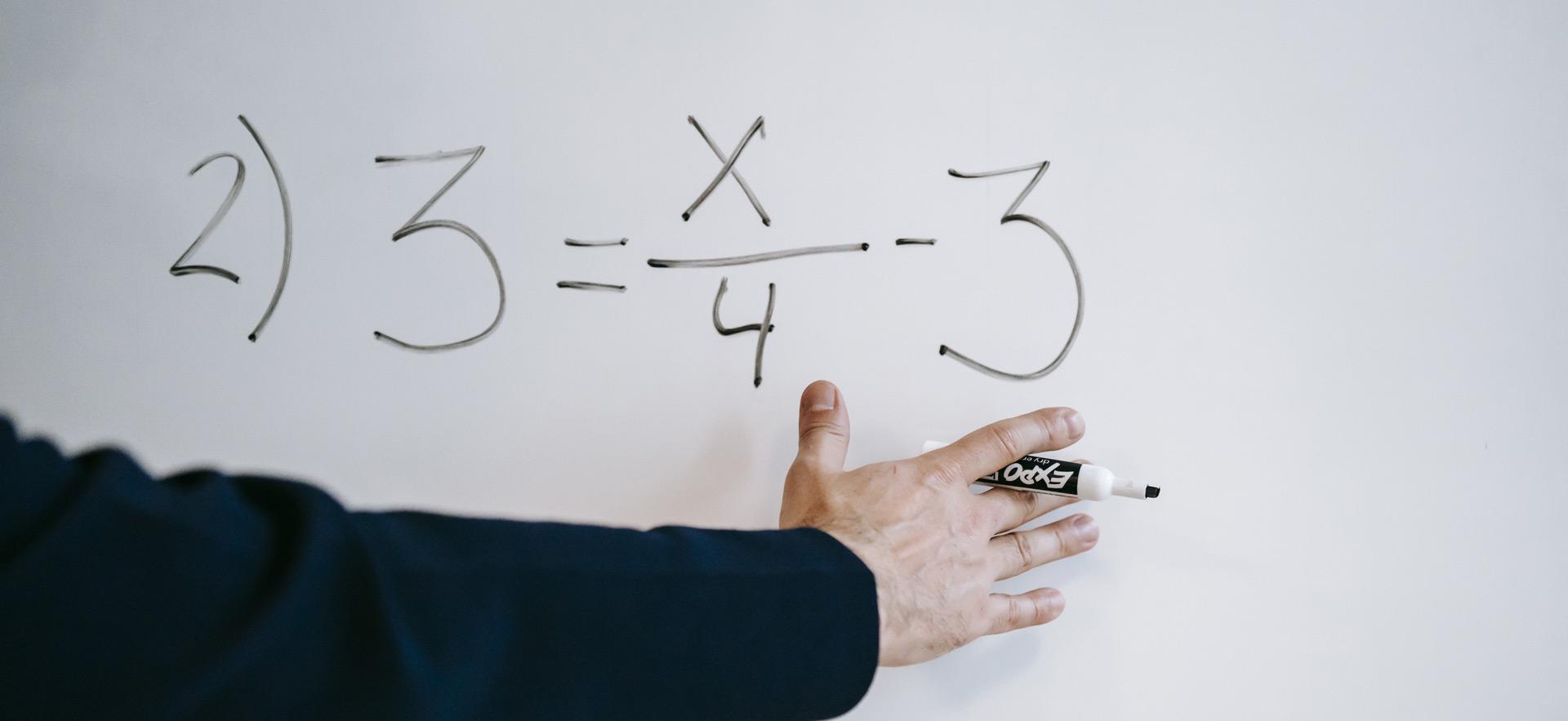 male working on math equation on white board