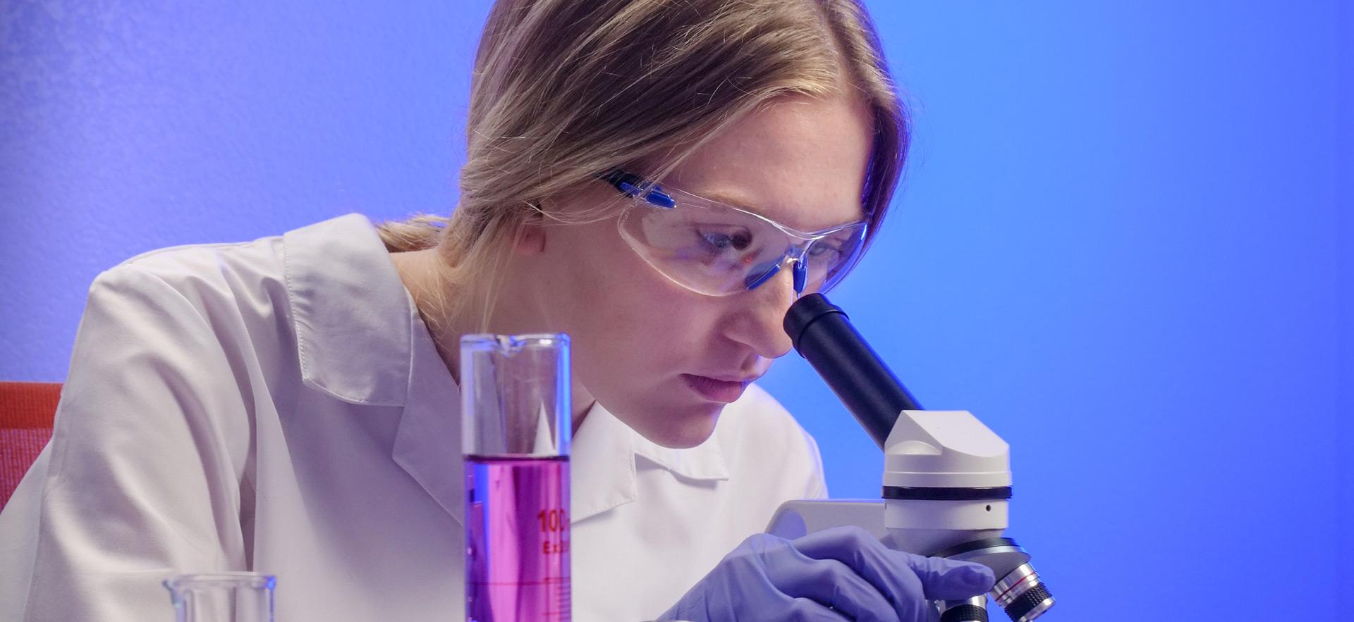 young woman looking through microscope