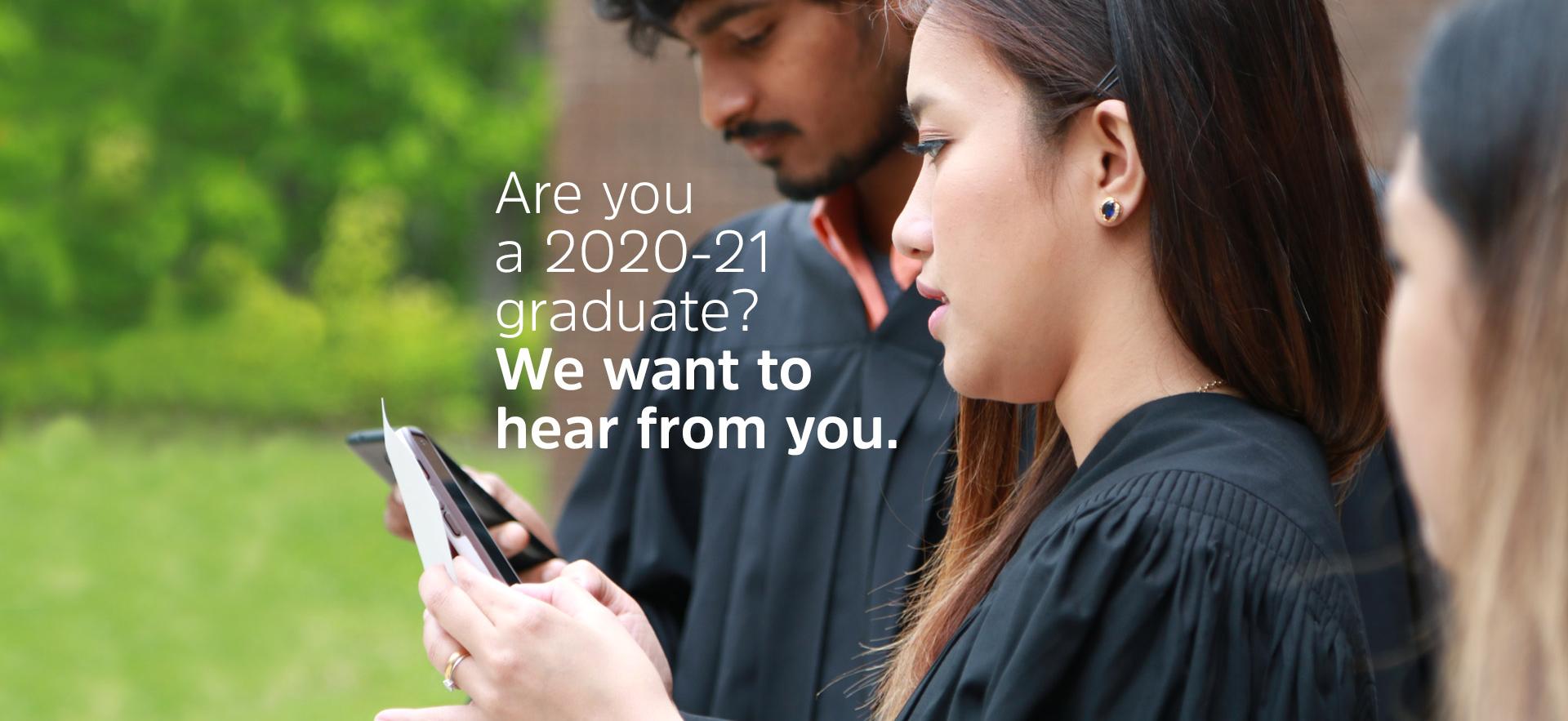 three grads in gowns standing together shown from the side with two looking at a phones