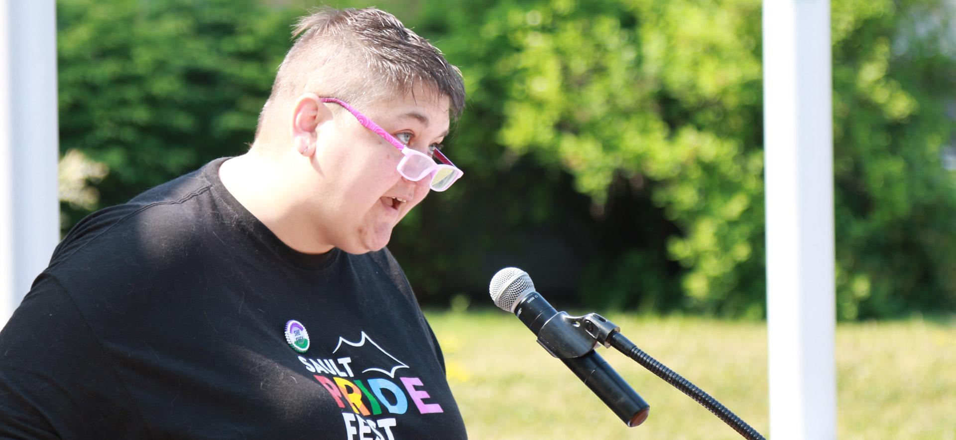 female with black shirt speaking at a podium 