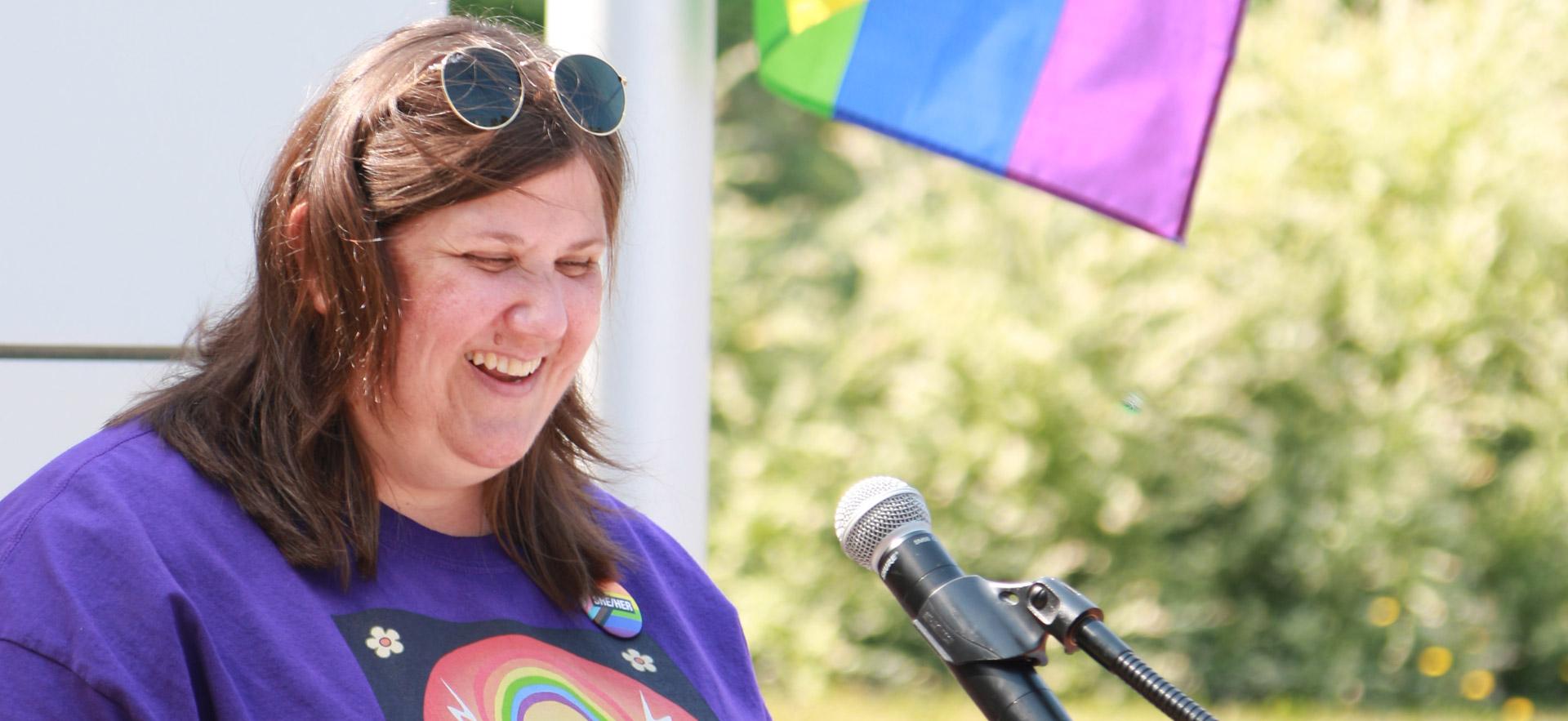 female with purple shirt speaking at a podium 