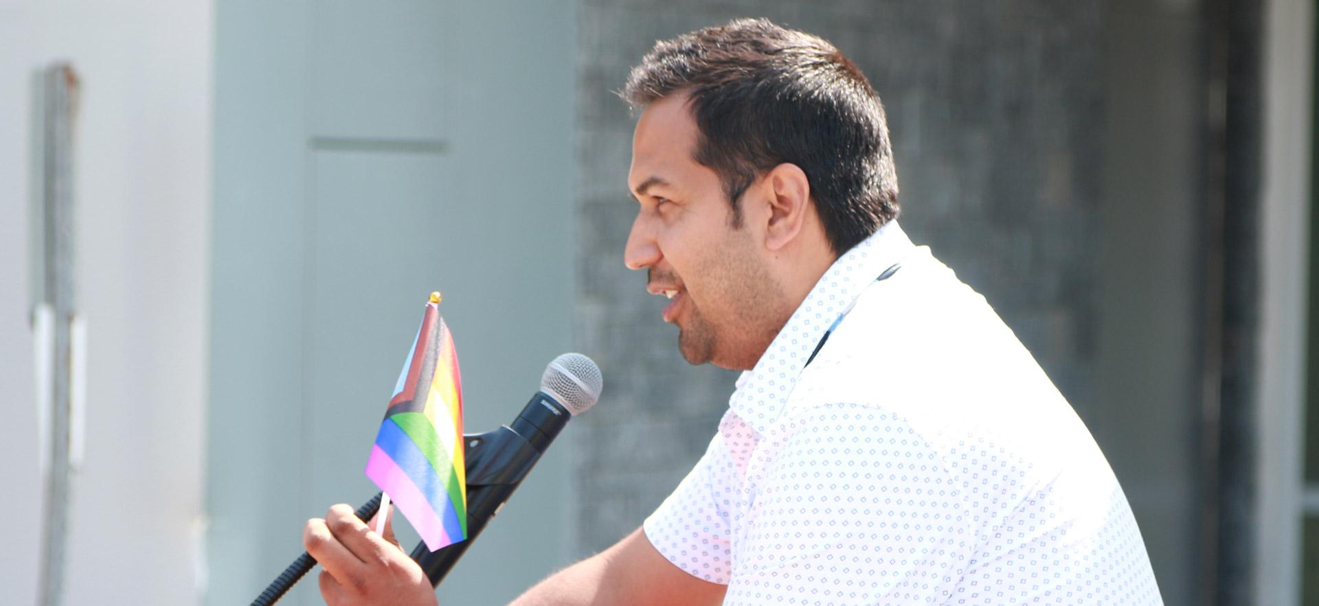 male with white shirt speaking at a podium 