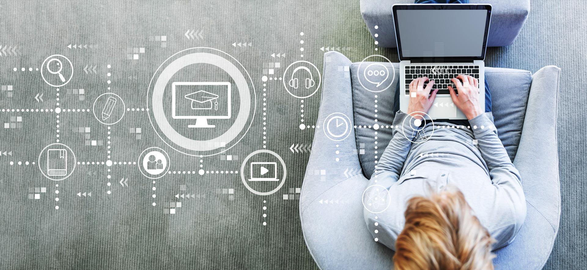 overhead view of person sitting on comfy chair with ottoman with laptop on lap while typing and icons added on screen for paths for e-learning tasks