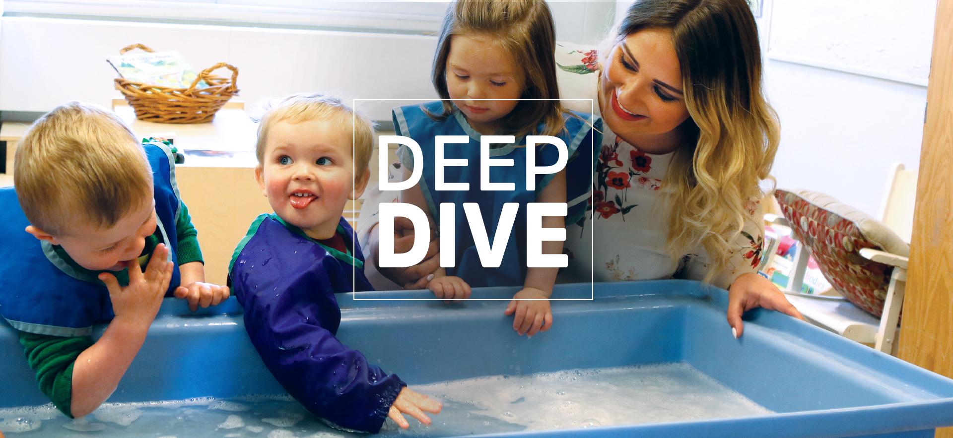 ECE smiling and kneeling down at a water table that three young children are playing at