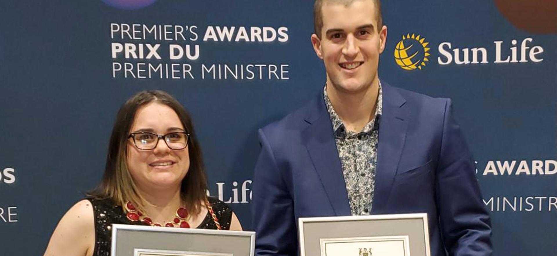 female and male standing straight forward holding rectangle certificates
