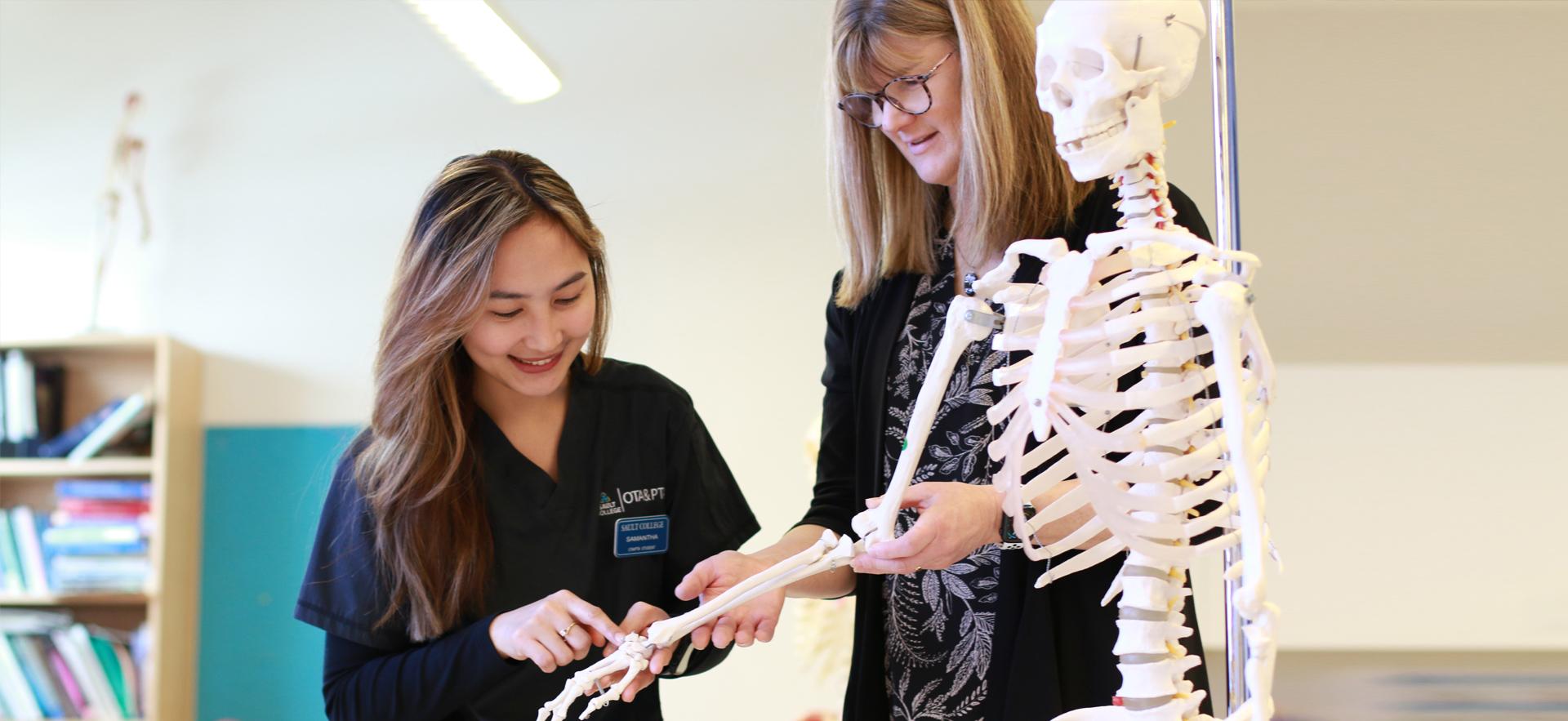OTA & PTA student and instructor looking at parts of body with a skeleton
