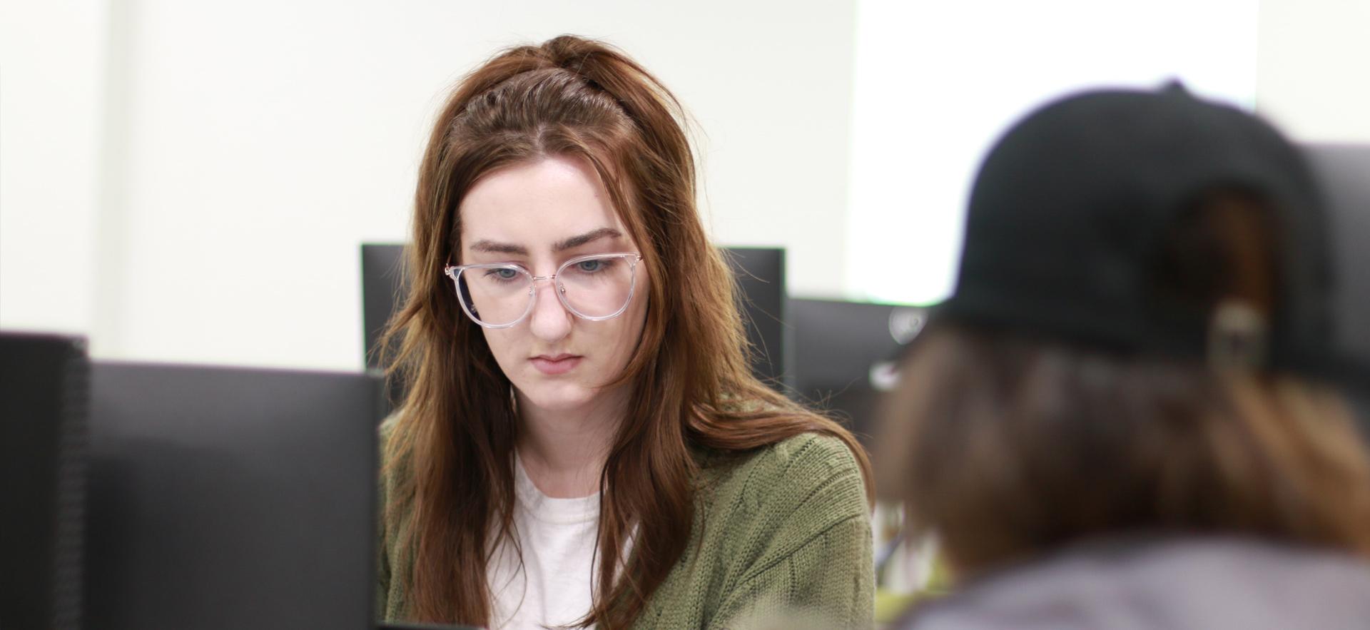 Business - Accounting student on computer in class helping a student at the Tax Clinic