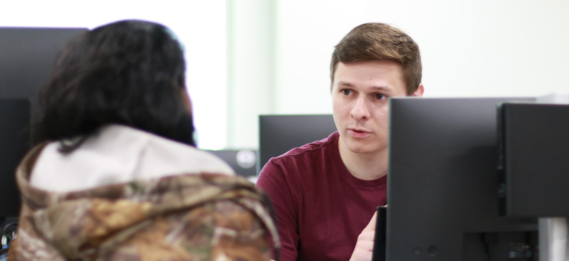 Business - Accounting student on computer in class helping a student at the Tax Clinic