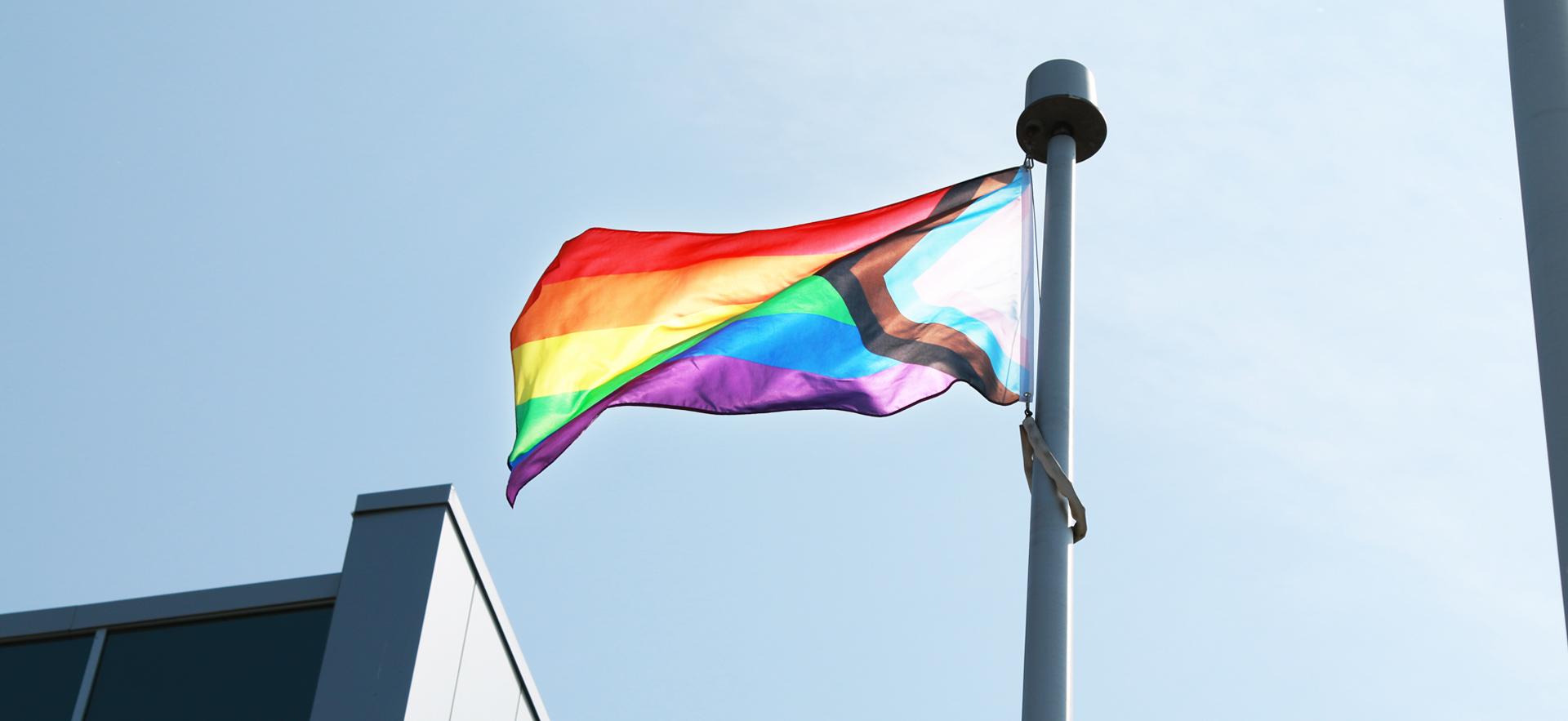 progress flag with red, orange, yellow, green, blue purple stripes blows in the wind