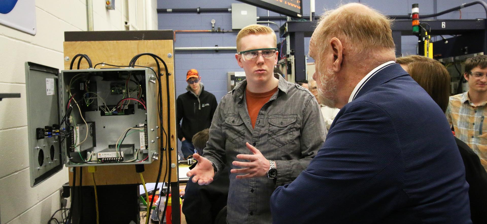 Engineering student speaking with Dr. Common in robotics lab