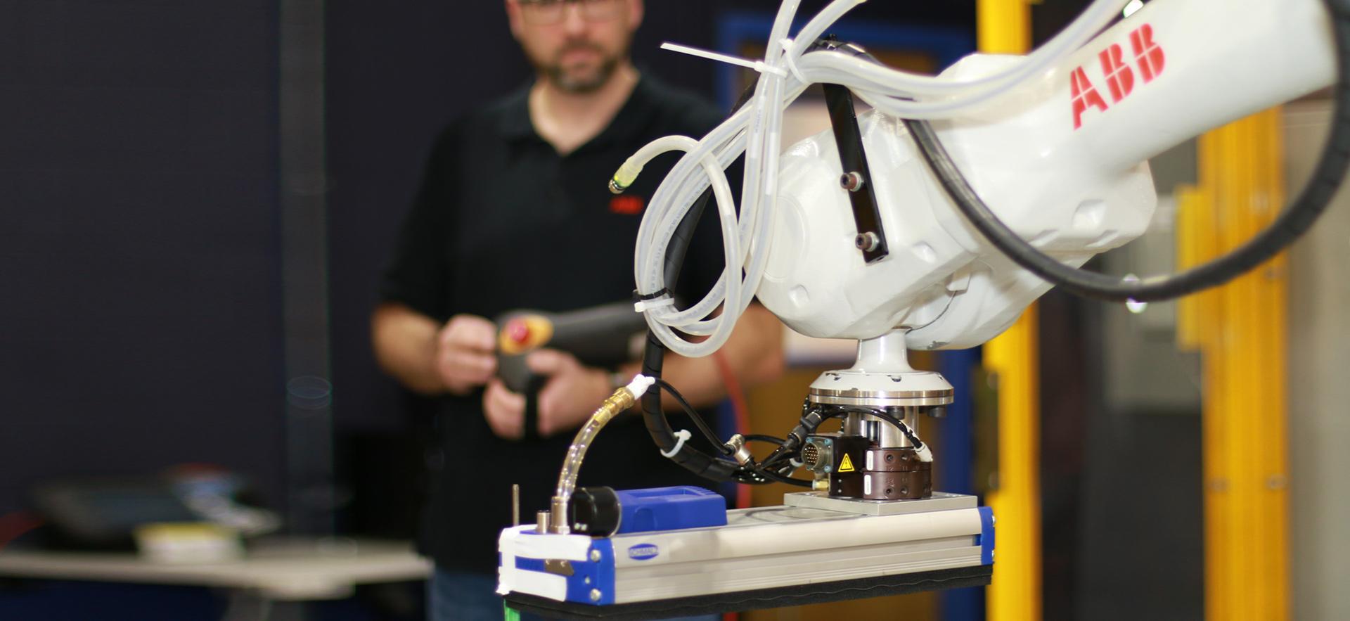 Engineering instructor in background controlling robotics equipment