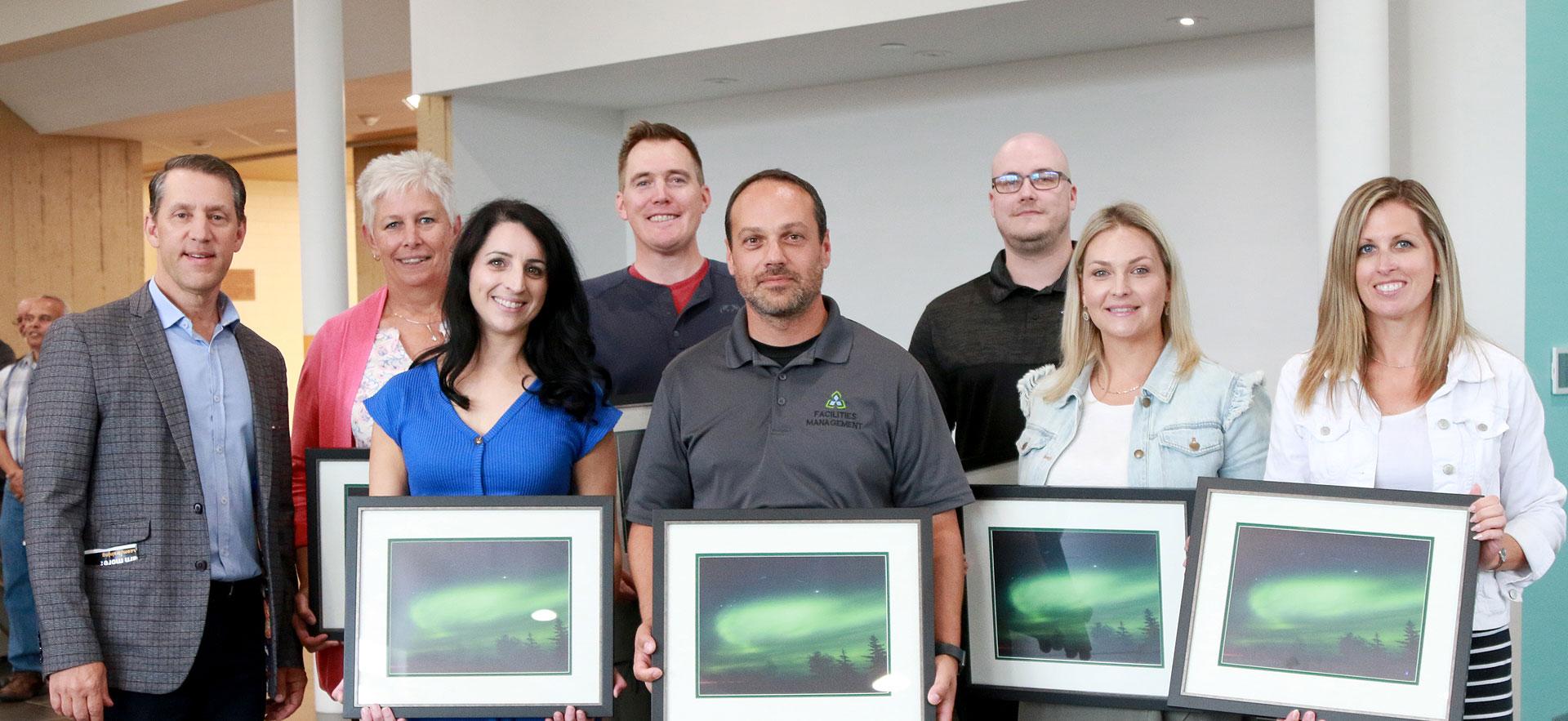 Award winners standing holding photo of northern lights