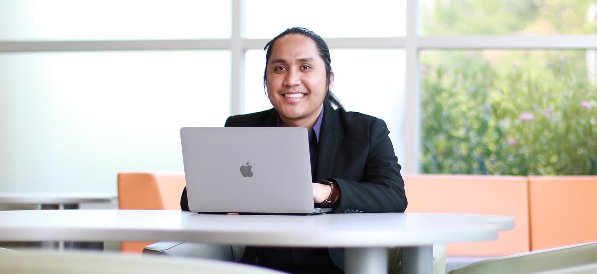 Paul a student of our Business - Accounting program smiling at camera sitting with laptop